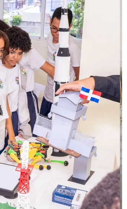 Estudiantes observando un cohete y una torre de lanzamiento impresos en 3D